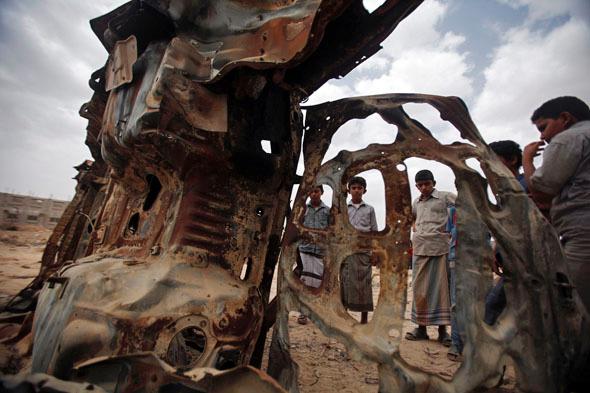 Boys gather near the wreckage of car destroyed last year by a U.S. drone air strike targeting suspected al Qaeda militants in Azan of the southeastern Yemeni province of Shabwa February 3, 2013.