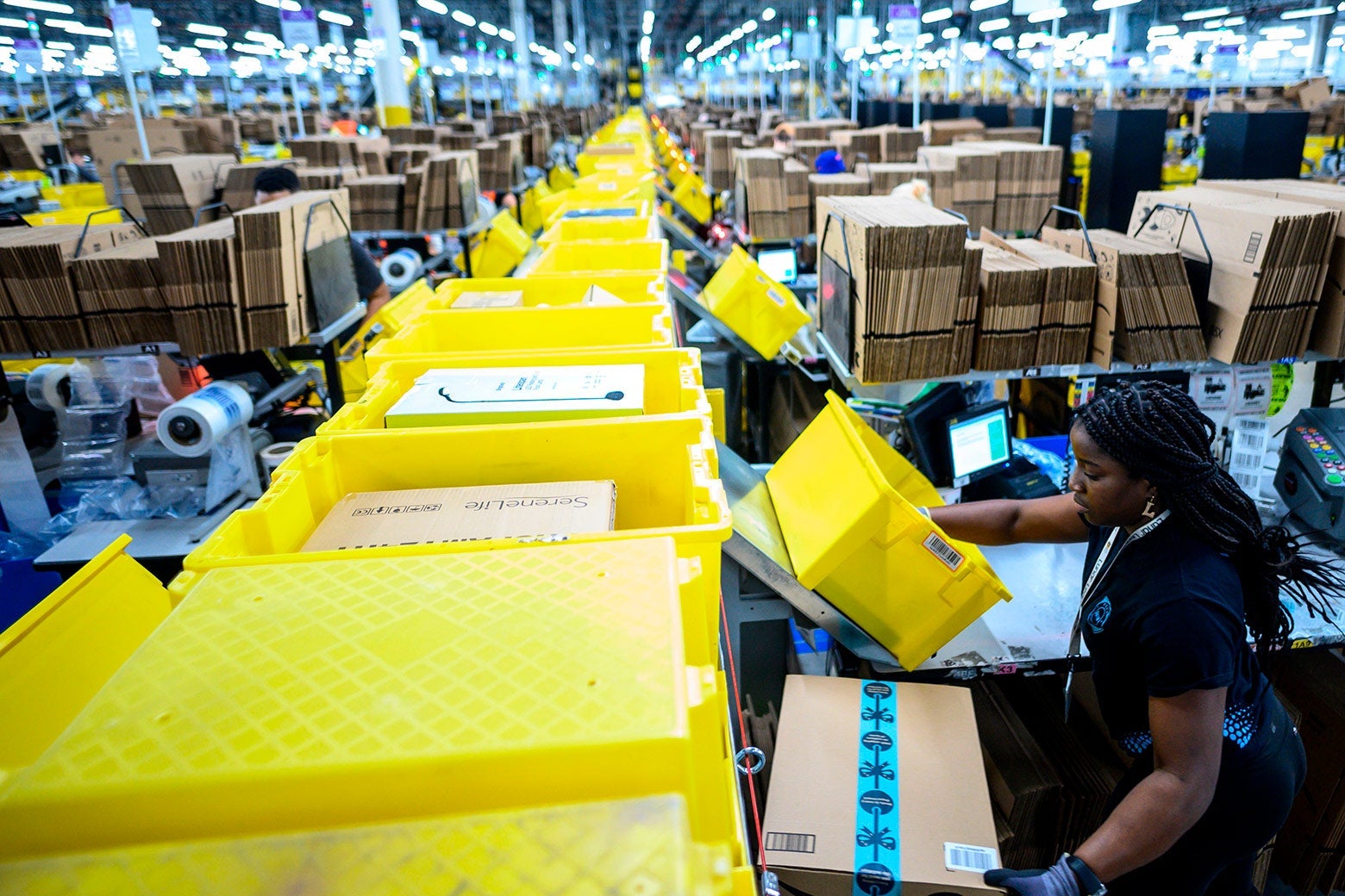 A woman works at a packing station at an Amazon fulfillment center.