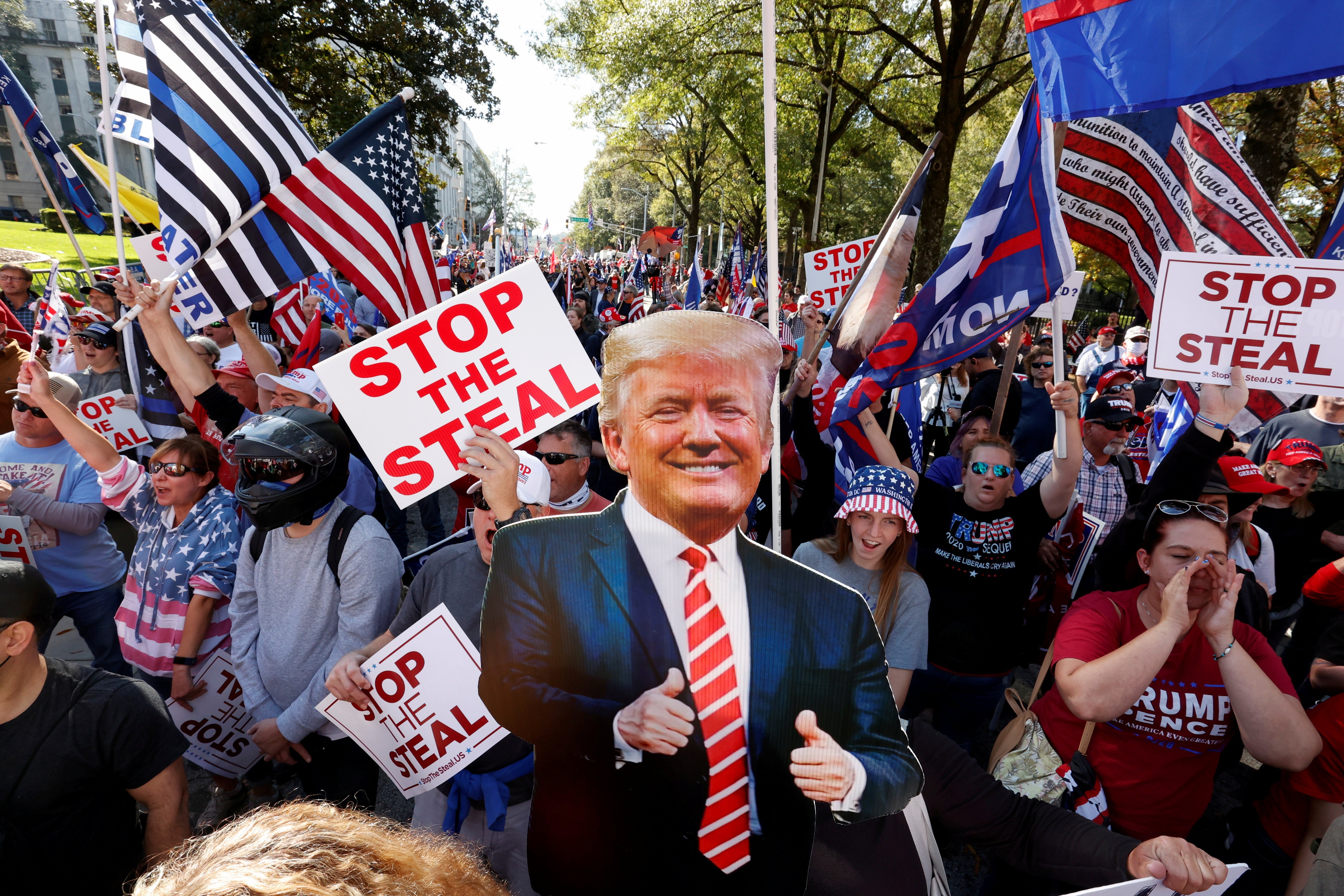 Cardboard cutout of Trump and people carrying "Stop the Steal" signs