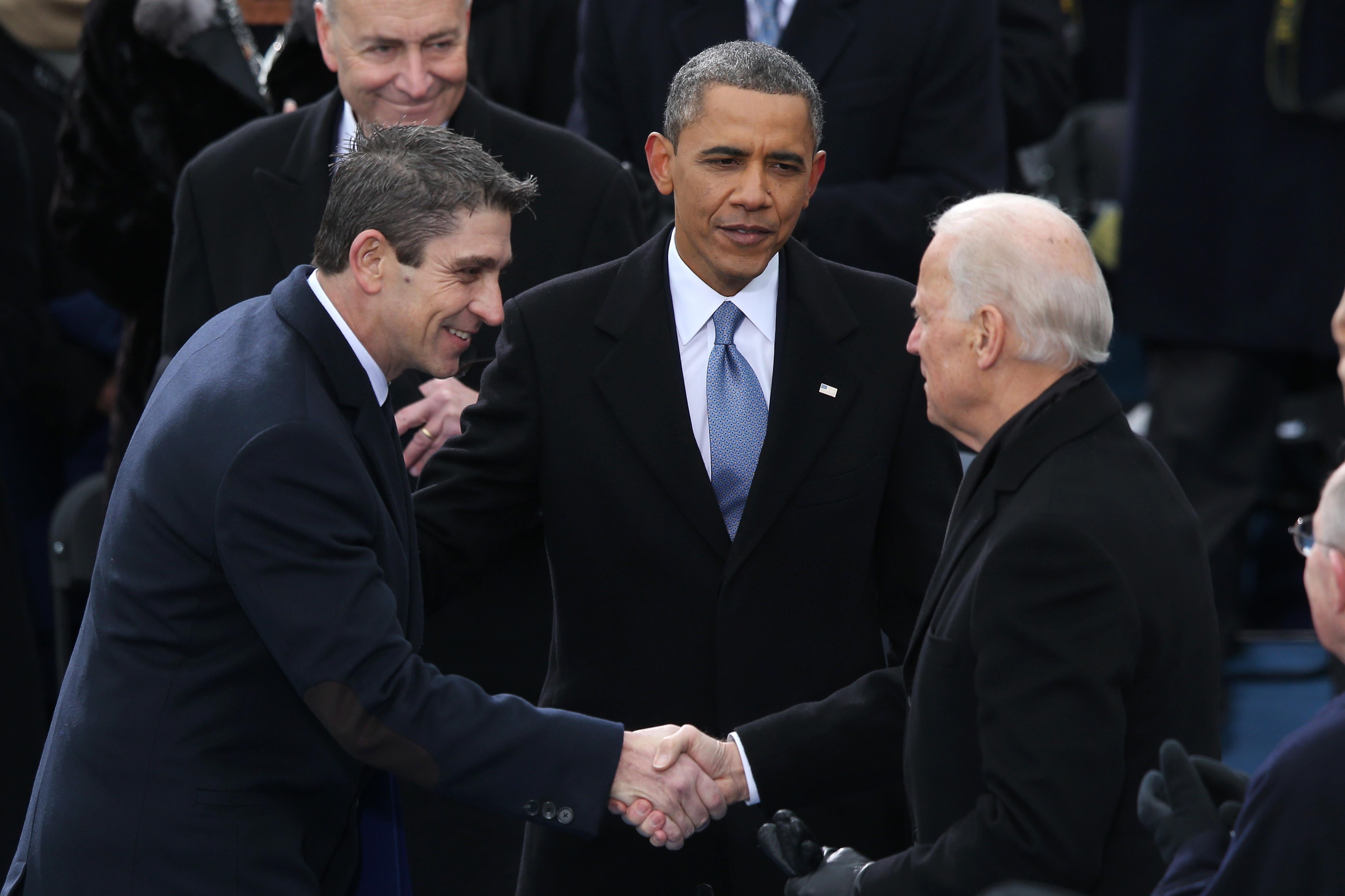 Richard Blanco shakes hands with Joe Biden while Obama stands behind them.