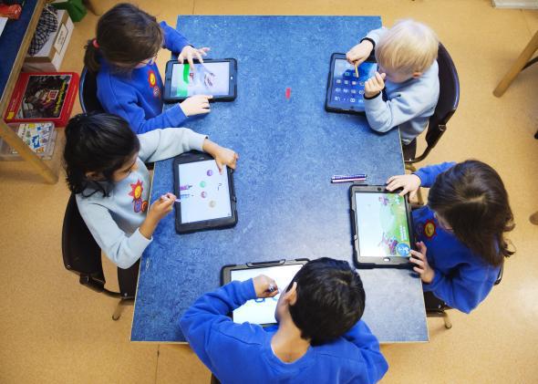 Nursery school students use iPads.