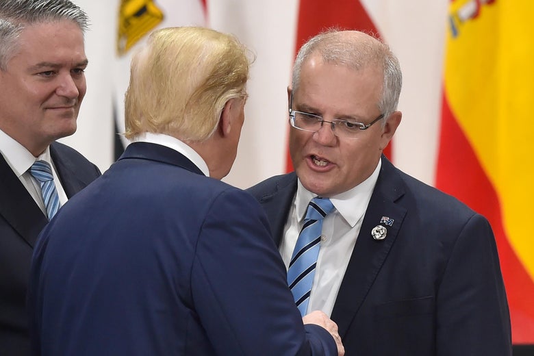 Scott Morrison leans in to talk to Donald Trump, who has his back to the camera.
