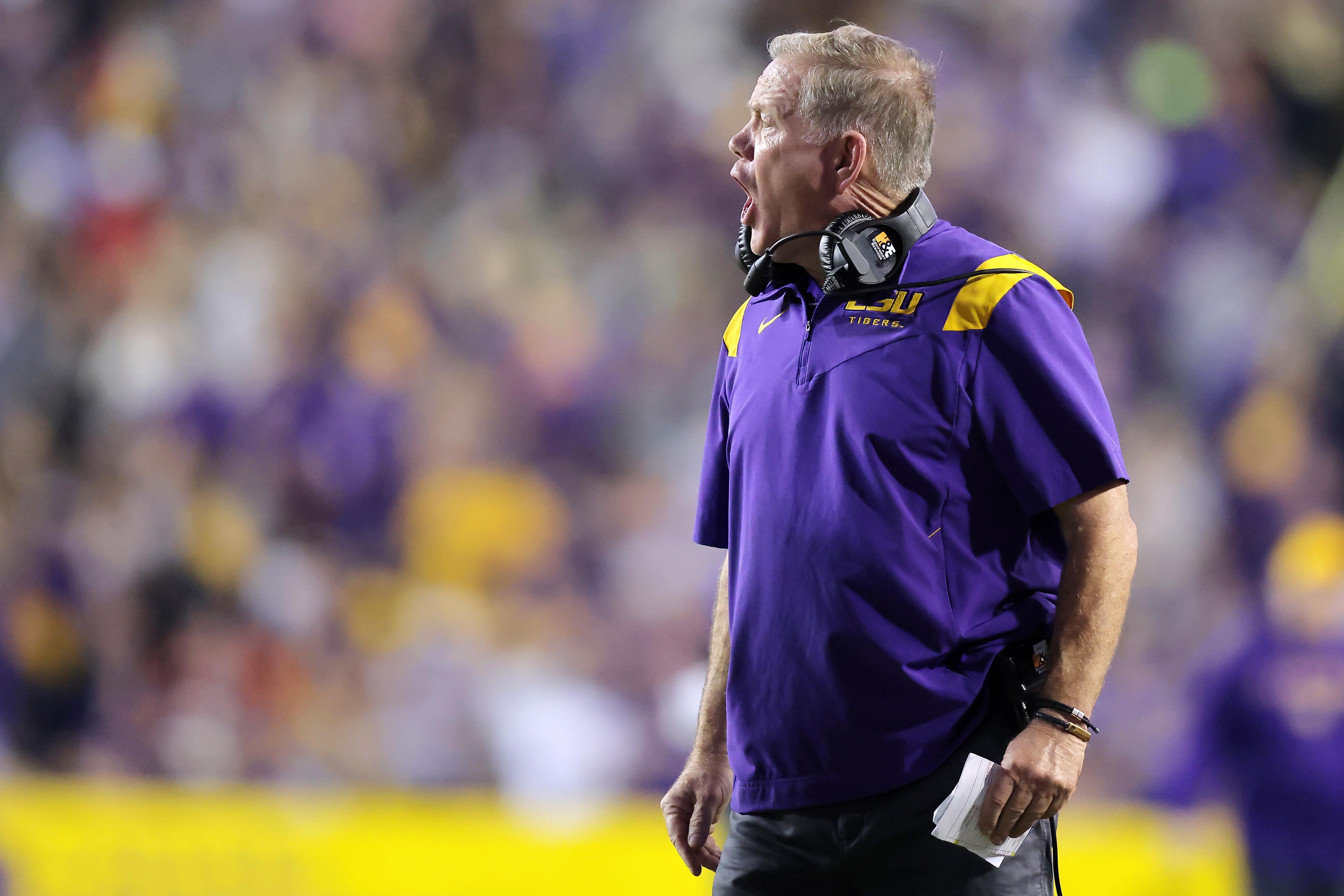 LSU football coach Brian Kelly stands on the sidelines and shouts.