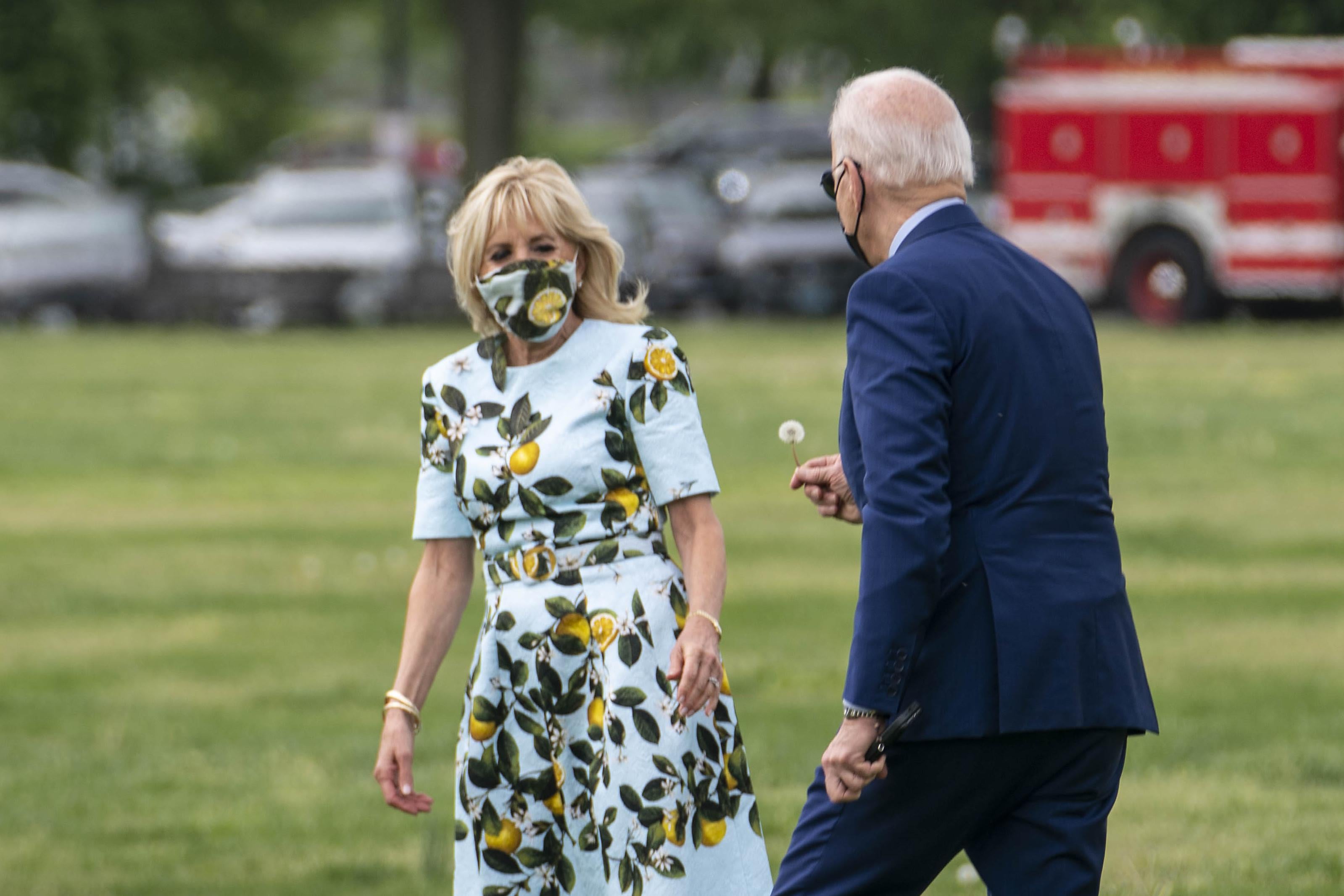 President Joe Biden picks a dandelion for first lady Jill Biden as they walk to Marine One on the Ellipse near the White House on April 29, 2021 in Washington, D.C.