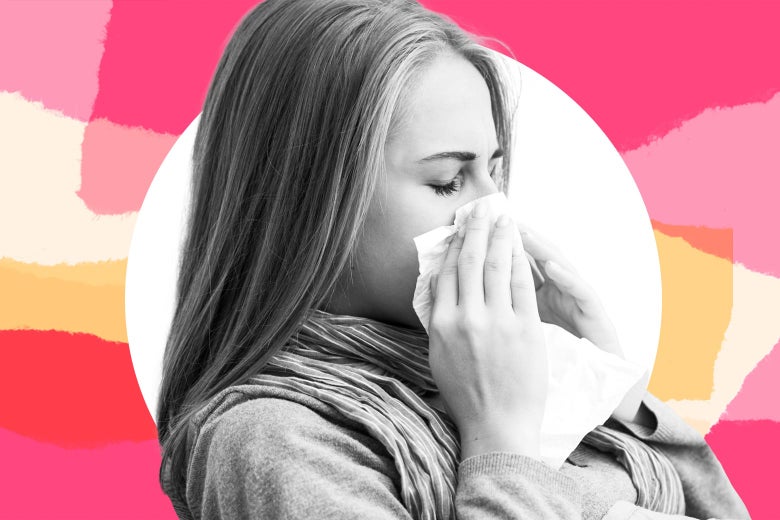 A teen girl sneezes into a tissue.