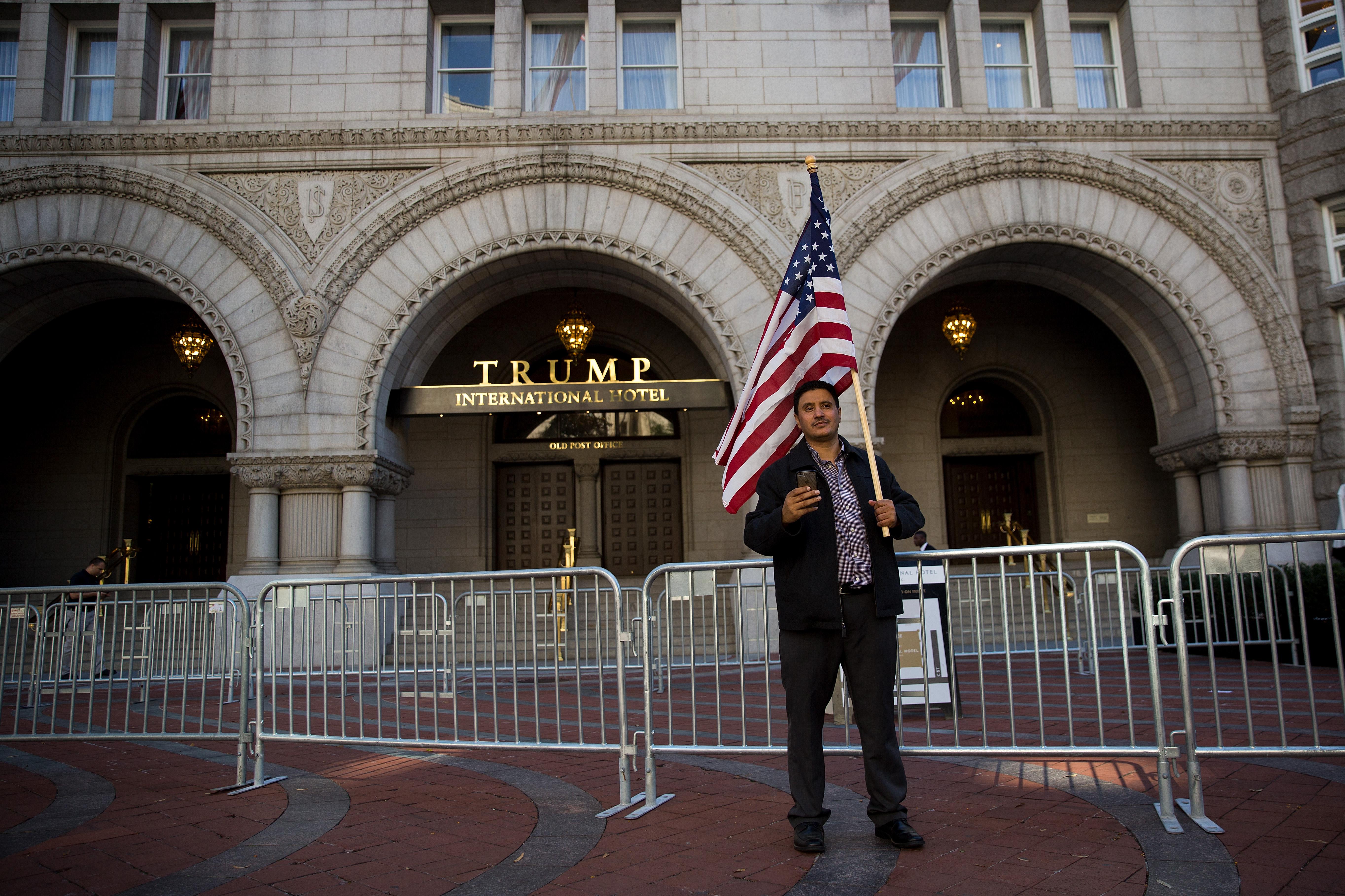 WASHINGTON, DC - OCTOBER 18: A man holds an American flag outside Trump International Hotel following a protest against the Trump administration's proposed travel ban, October 18, 2017 in Washington, DC. Early Wednesday morning, a federal judge in Maryland granted a motion for a preliminary injunction on the administration's travel ban. This is the Trump administration's third attempt to restrict entry into the United States for citizens from mostly Muslim-majority countries. The Department of Justice said it plans to appeal and the White House issued a statement calling the judge's decision 'dangerously flawed.' (Photo by Drew Angerer/Getty Images)