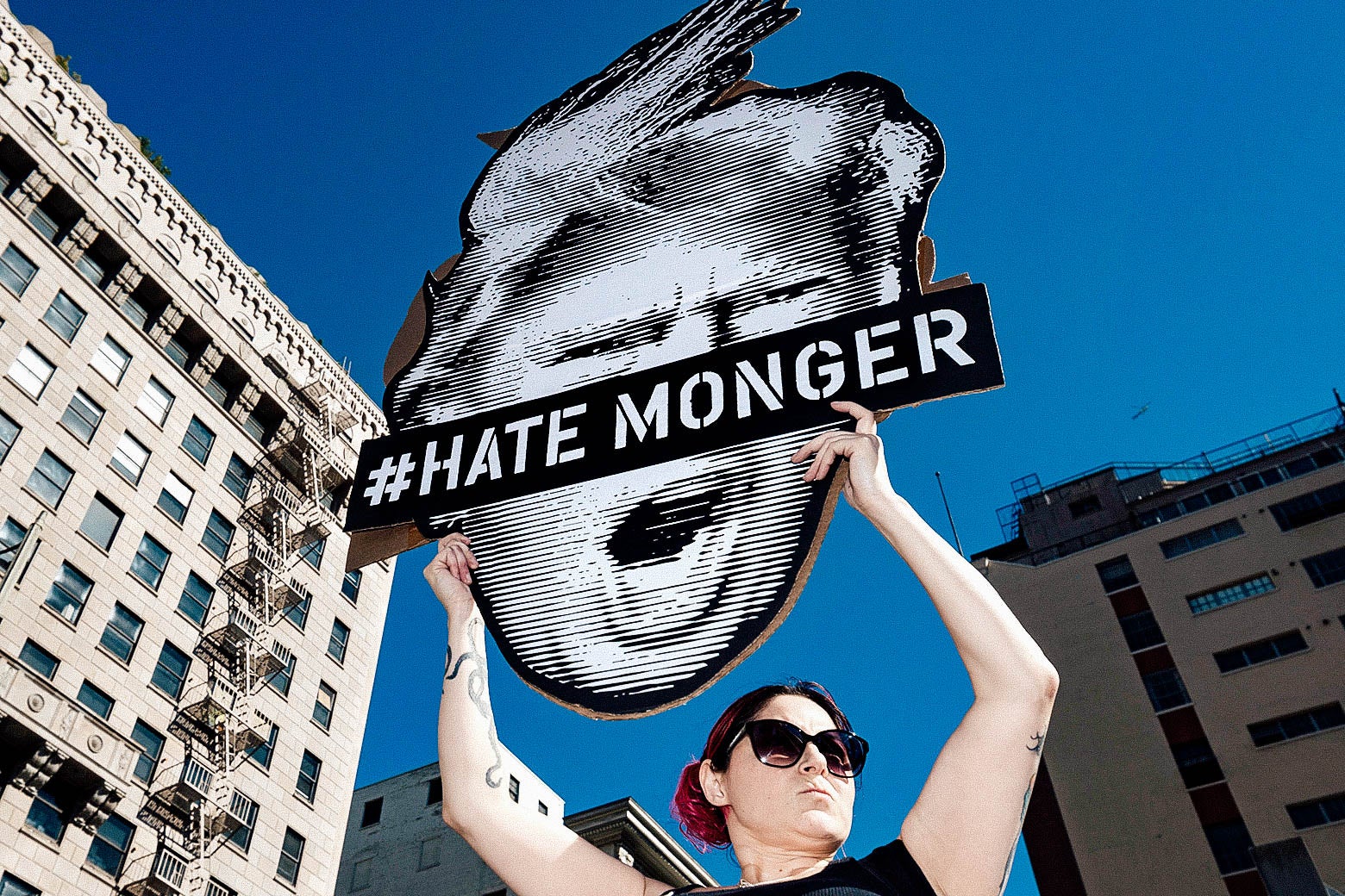 A protester holds up a sign with Donald Trump's face and the words #Hate Monger.