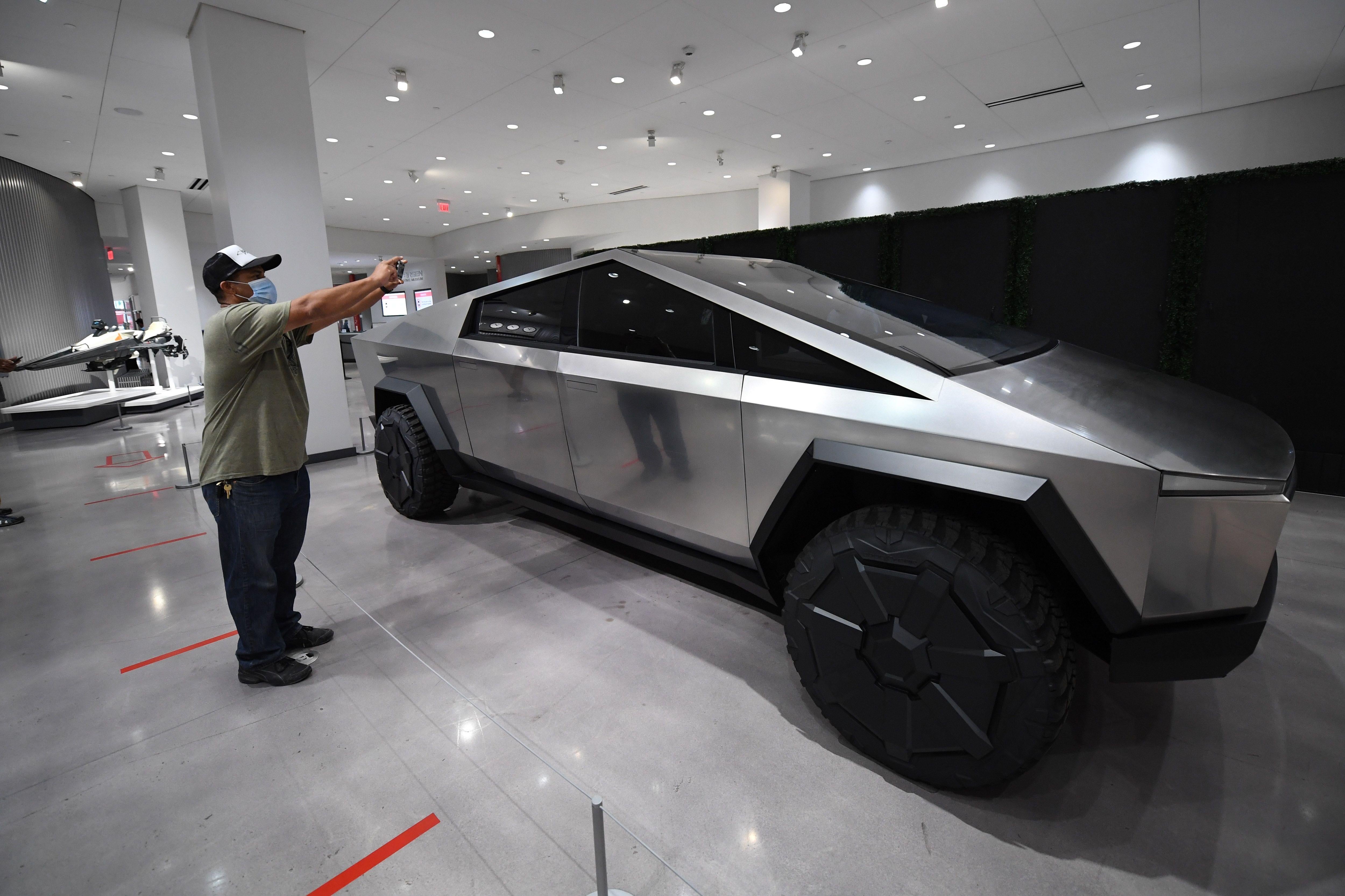 Visitors wearing face coverings view the Telsa Cybertruck at the recently reopened Petersen Automotive Museum in Los Angeles, California, July 1, 2020.  California Governor Gavin Newsom announced July 1, 2020 that the state would be shutting down indoor operations for restaurants, zoos, museums and several other sectors effective immediately due to concerns over the recent spike in COVID-19 cases. - California Governor Gavin Newsom announced July 1, 2020 that the state would be shutting down indoor operations for restaurants, zoos, museums and several other sectors effective immediately due to concerns over the recent spike in COVID-19 cases. (Photo by Robyn Beck / AFP) (Photo by ROBYN BECK/AFP via Getty Images)