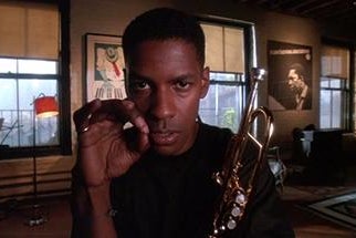 Denzel Washington as Bleek holds a trumpet.