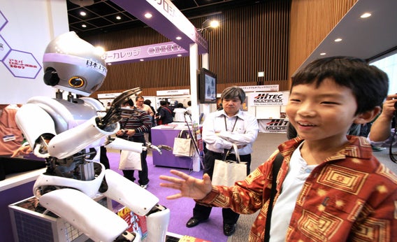 A boy plays rock paper scissors with a humanoid robot in Tokyo.