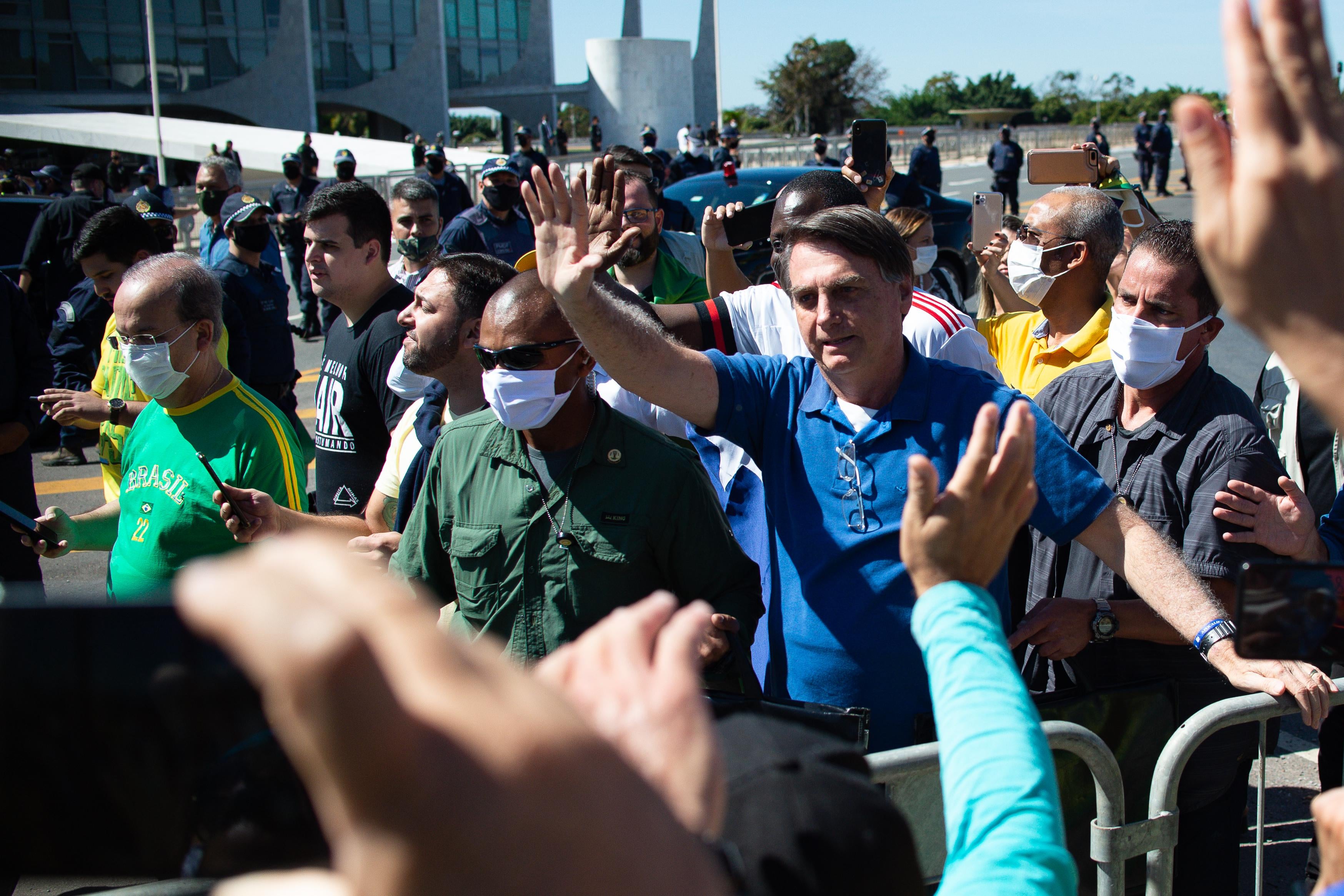 A maskless Bolsonaro waves to a crowd.