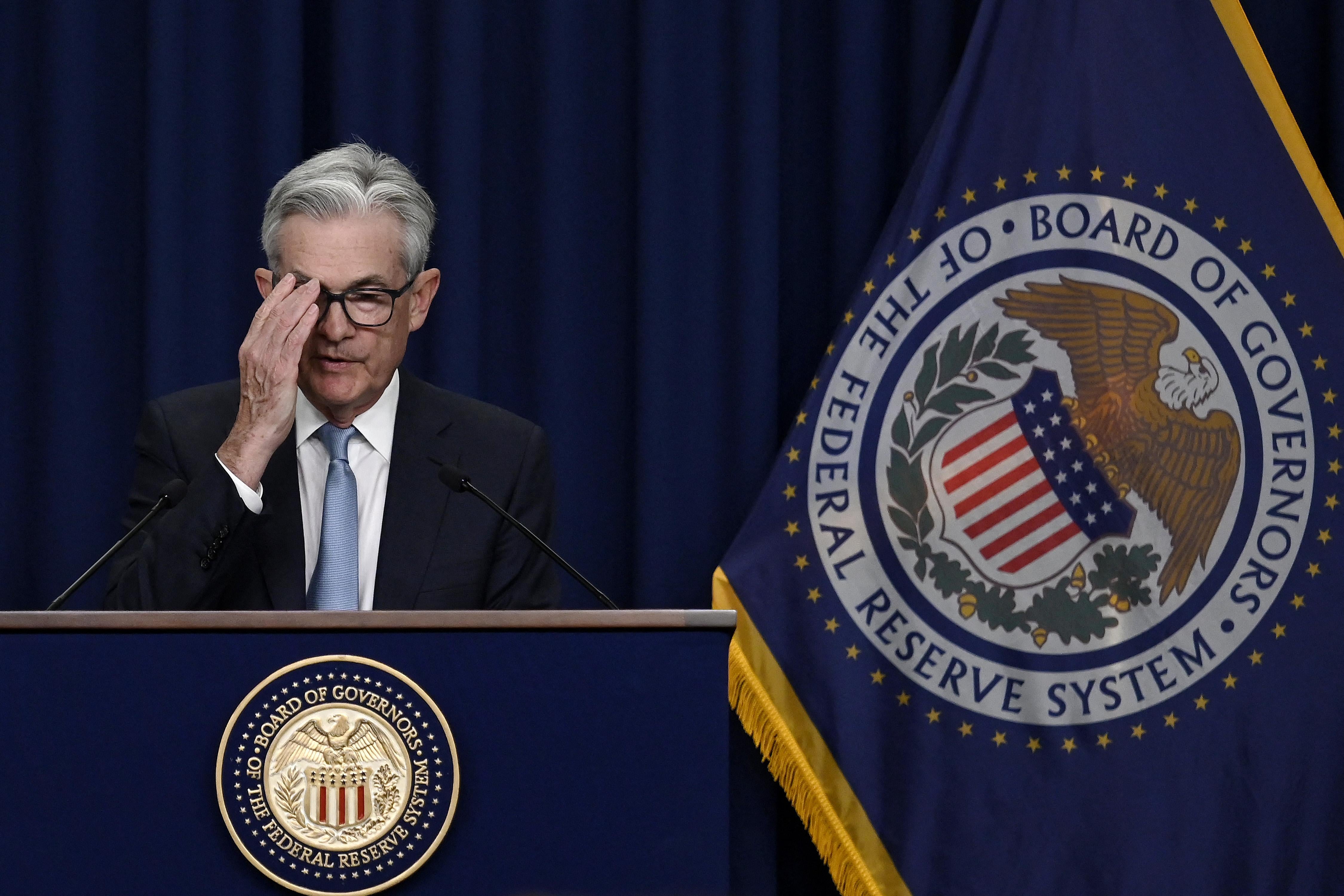 Powell adjusts his glasses as he speaks at a podium