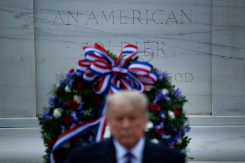 Donald Trump in front of a monument with a wreath laid on it.