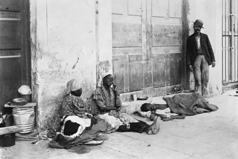 Refugees sit and lay on the sidewalk in this historic black-and-white photo.