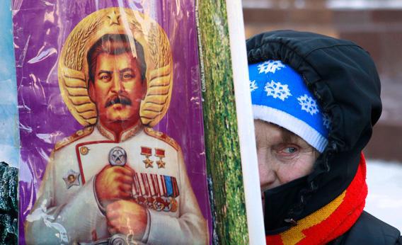 A woman holds a poster illustrating the late Soviet leader Josef Stalin before a ceremony to mark the 60th anniversary of his death in Red Square in central Moscow March 5, 2013.