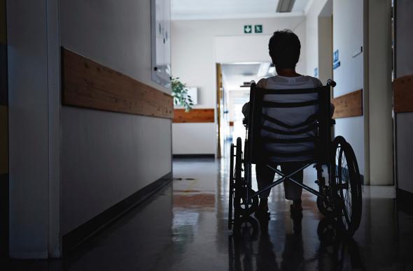 Person in a wheelchair in a darkened hospital corridor.