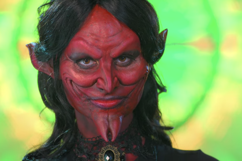 Woman wearing a pointed red devil mask.