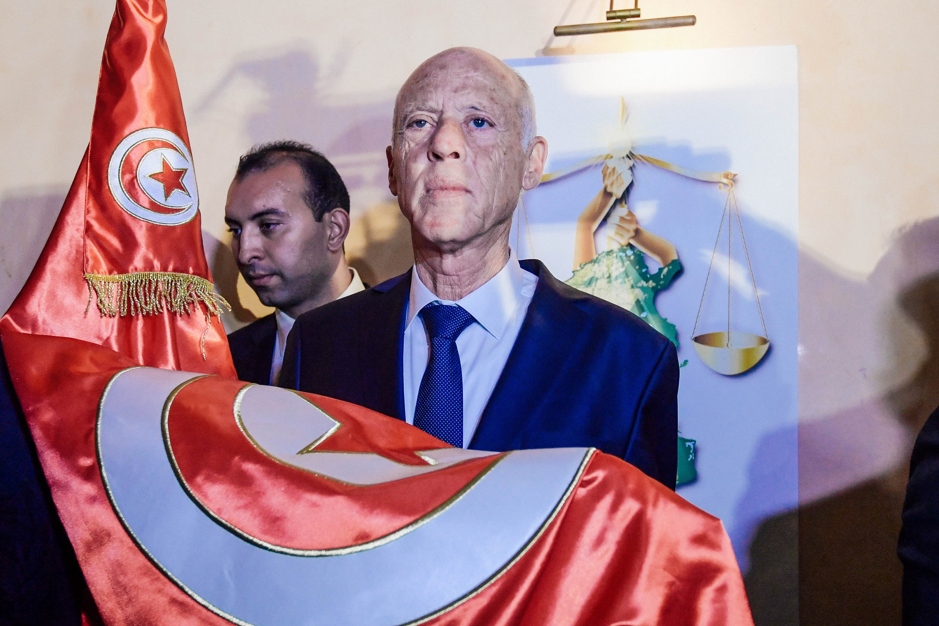 Kais Saied holds the Tunisian flag in his hands.
