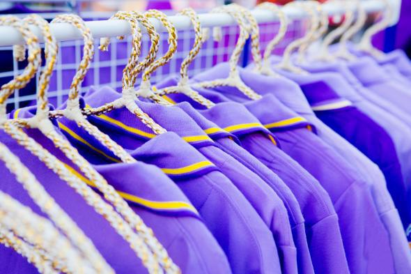 A series of purple shirts hanging on a rack
