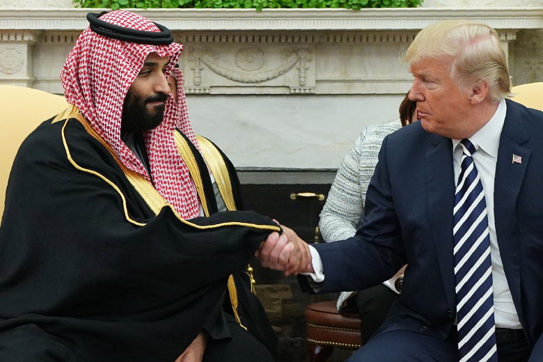 Mohammed bin Salman and Donald Trump, seated, shake hands.