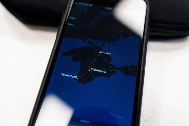 A phone shows a map of the Crimean peninsula. 