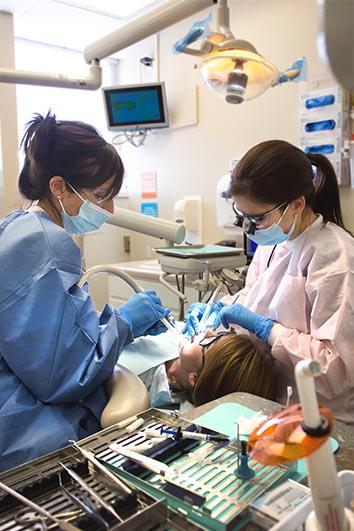 Dentist Dr. Yesylle White (right) and dental assistant, Natalia Hernandez (left) performing dentistry.