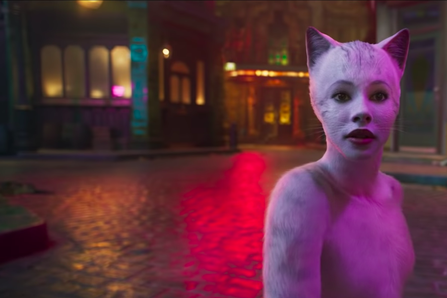 Francesca Howard as Victoria the cat on a lamp lit street.