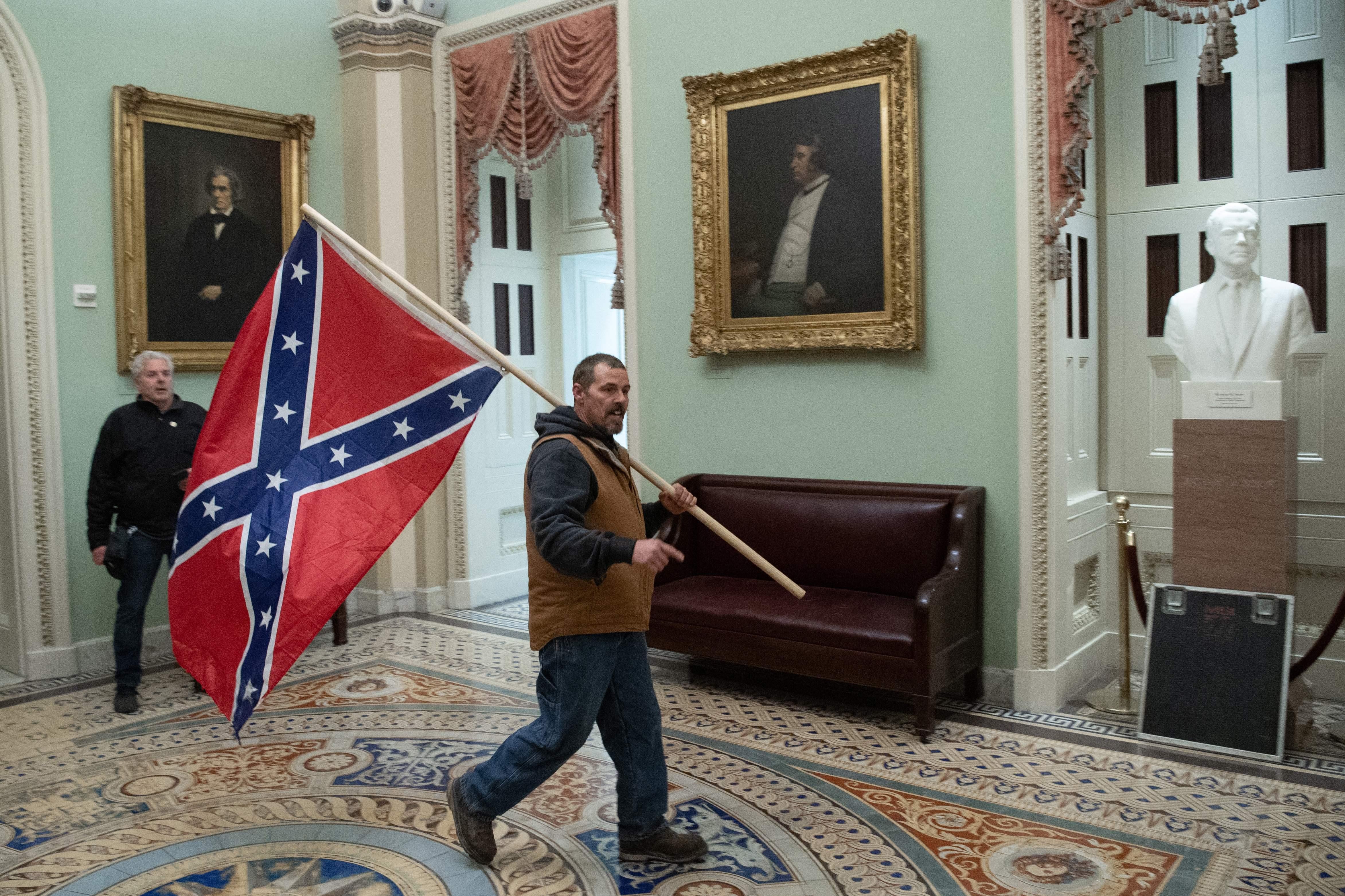 A man carries a Confederate flag through a hallway inside the Capitol