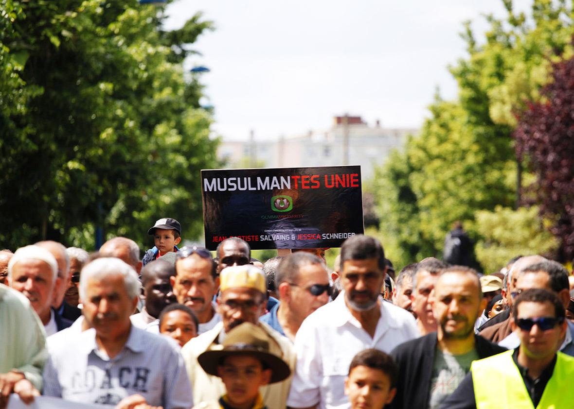 A participant holds up a placard reading "Muslims-Mantes United" as people take part on June 19, 2016 in Mantes-la-Jolie in a silent march in memory of the French police officer and his partner stabbed to death on June 13 by a convicted extremist who had pledged allegiance to the Islamic State group. 