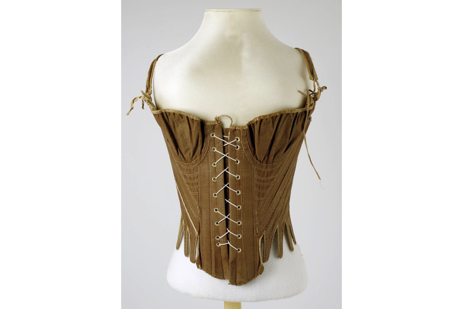 A dark brown corset on a torso model. It is laced up the frost and has loose pouches for the breasts.