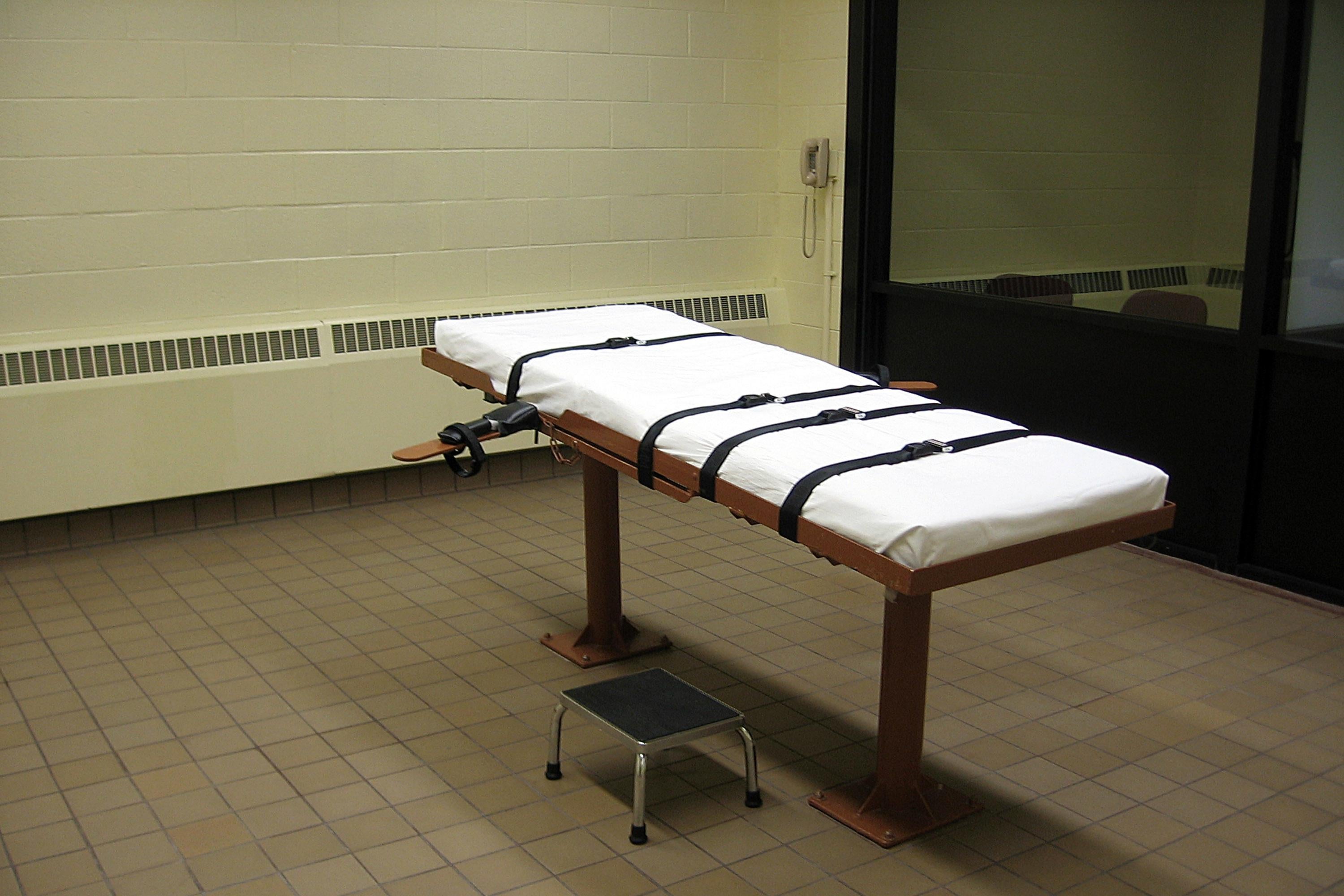 A cot with straps in an execution chamber.