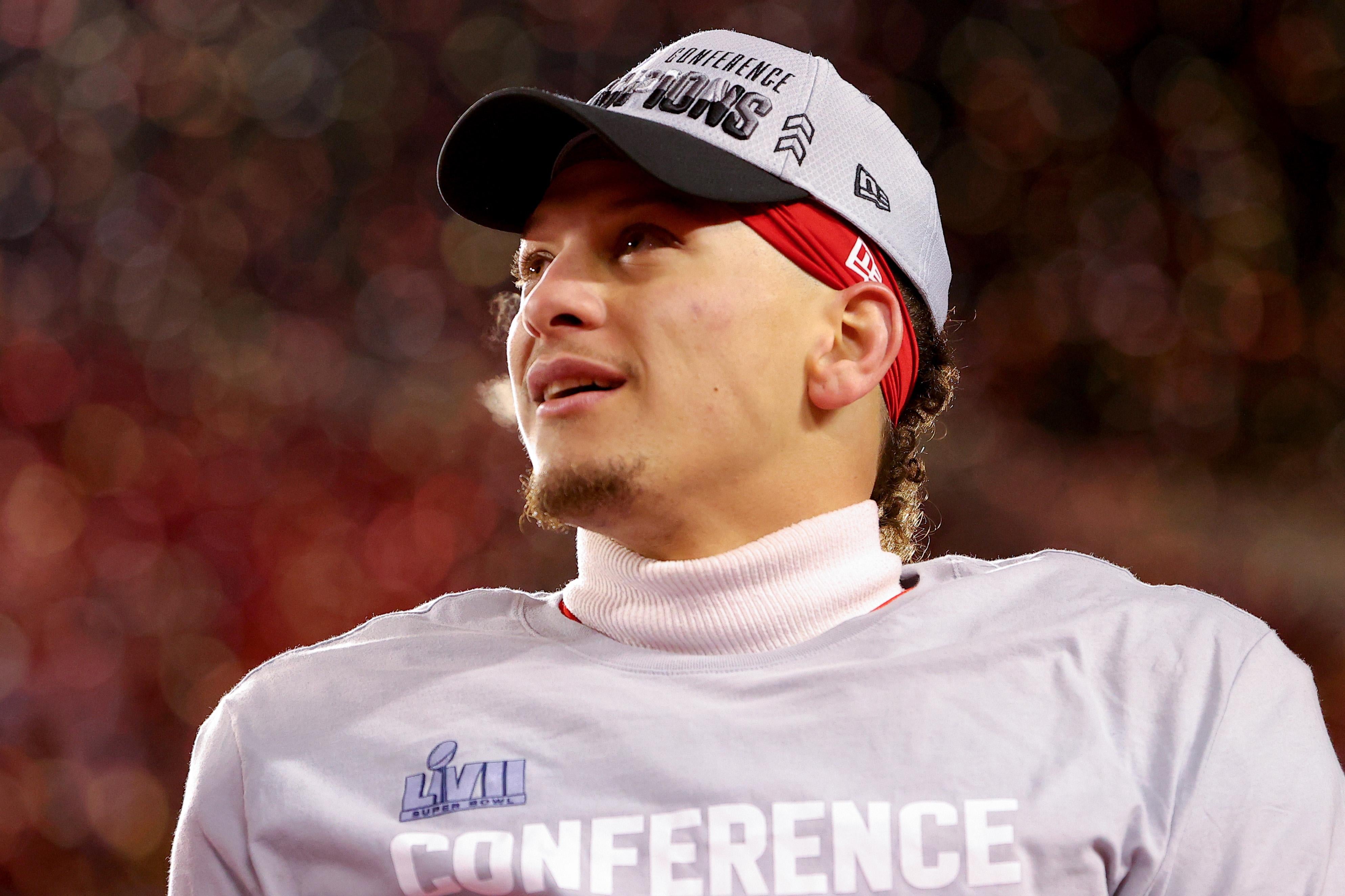 Mahomes gazes upward in his champtionship hat and T-shirt, a slight smile on his face, with confetti falling behind him