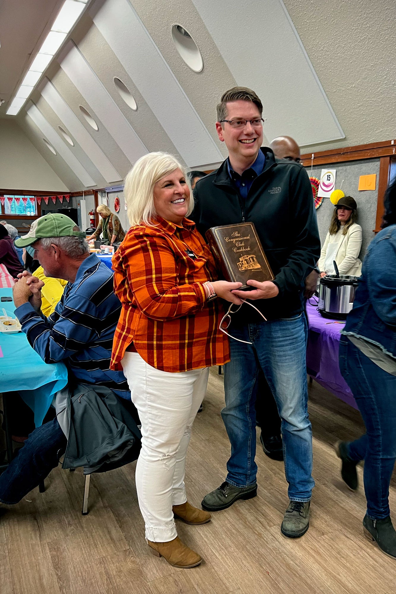 Nick Begich and a blond woman hold up the cookbook.