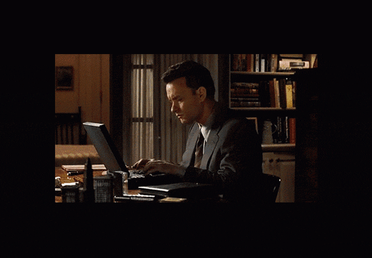 A gif of Tom Hanks typing earnestly on a laptop at night in a home office. 
