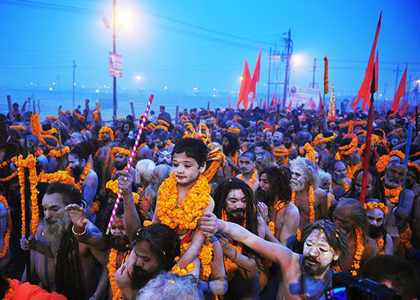 Hindu holy men carry a child adorned with marigold flowers on their shoulders as they march toward the Sangham during the Kumbh Mela on Jan. 14, 2013, in Allahabad, India.