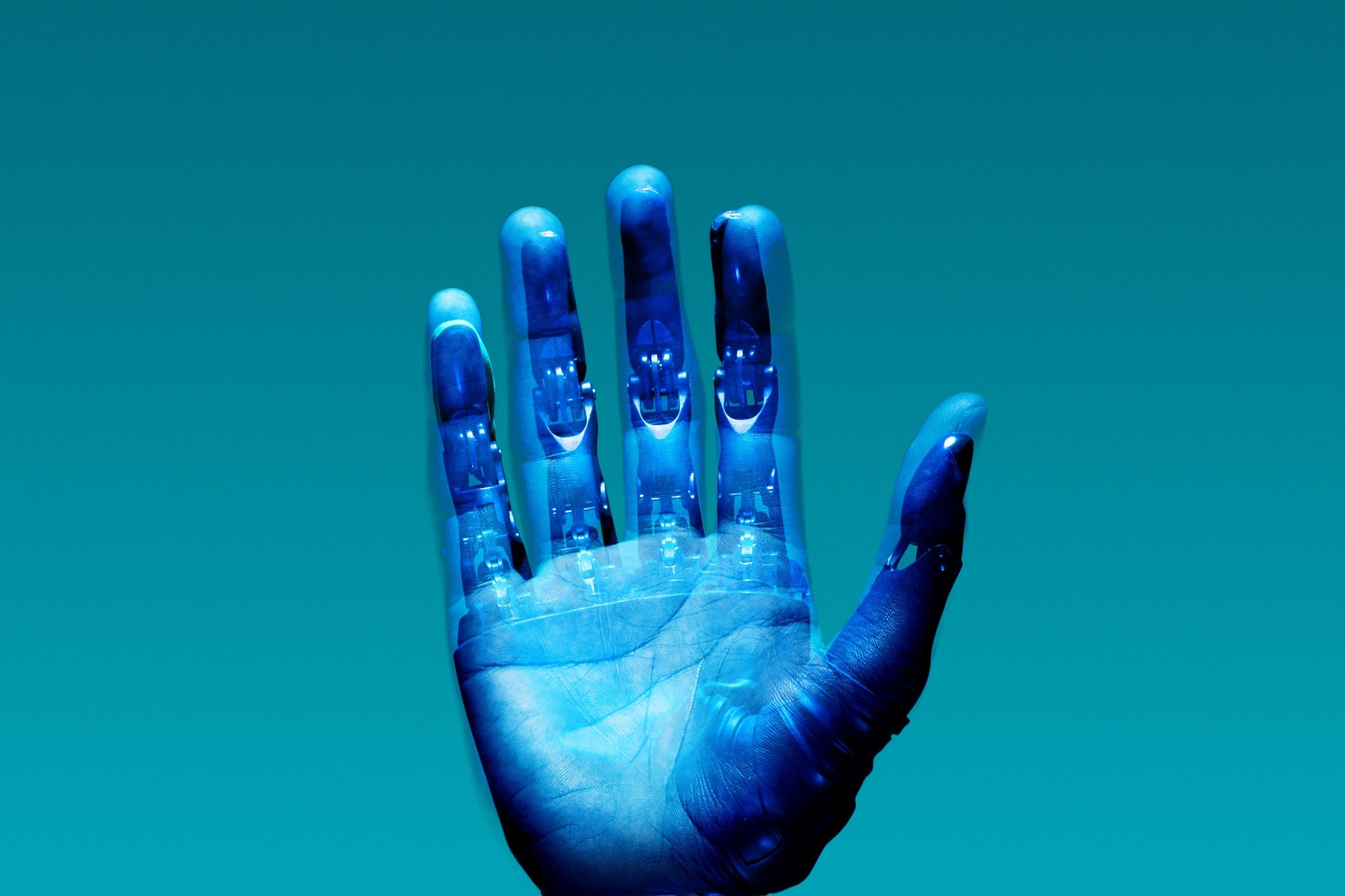 A hand bathed in blue light, superimposed with electronics.