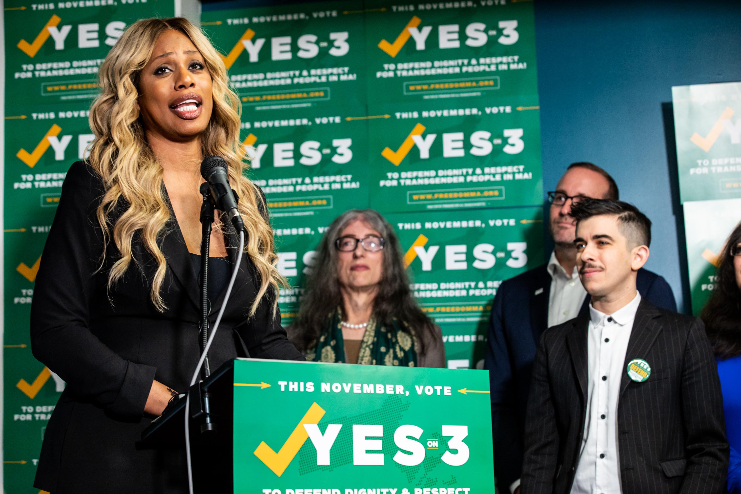 Laverne Cox speaks at a lectern with other activists.