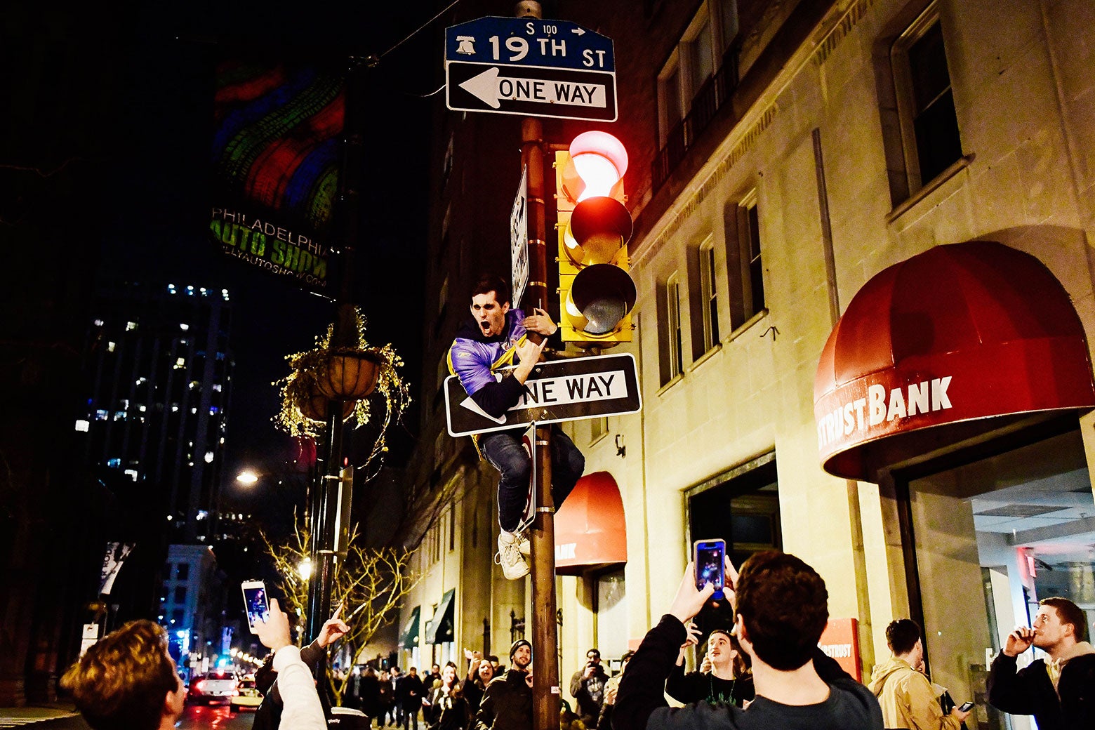 A fan climbs a pole reacting to Super Bowl LII on Walnut Street near City Hall on Sunday in downtown Philadelphia.