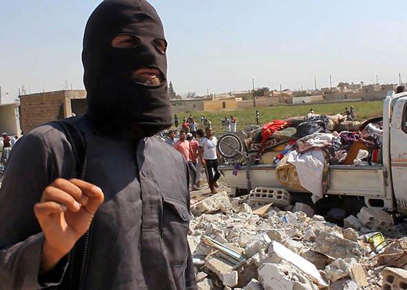 a jihadist from the Islamic State (IS) group standing on the rubble of houses after a Syrian warplane was reportedly shot down by IS militants.