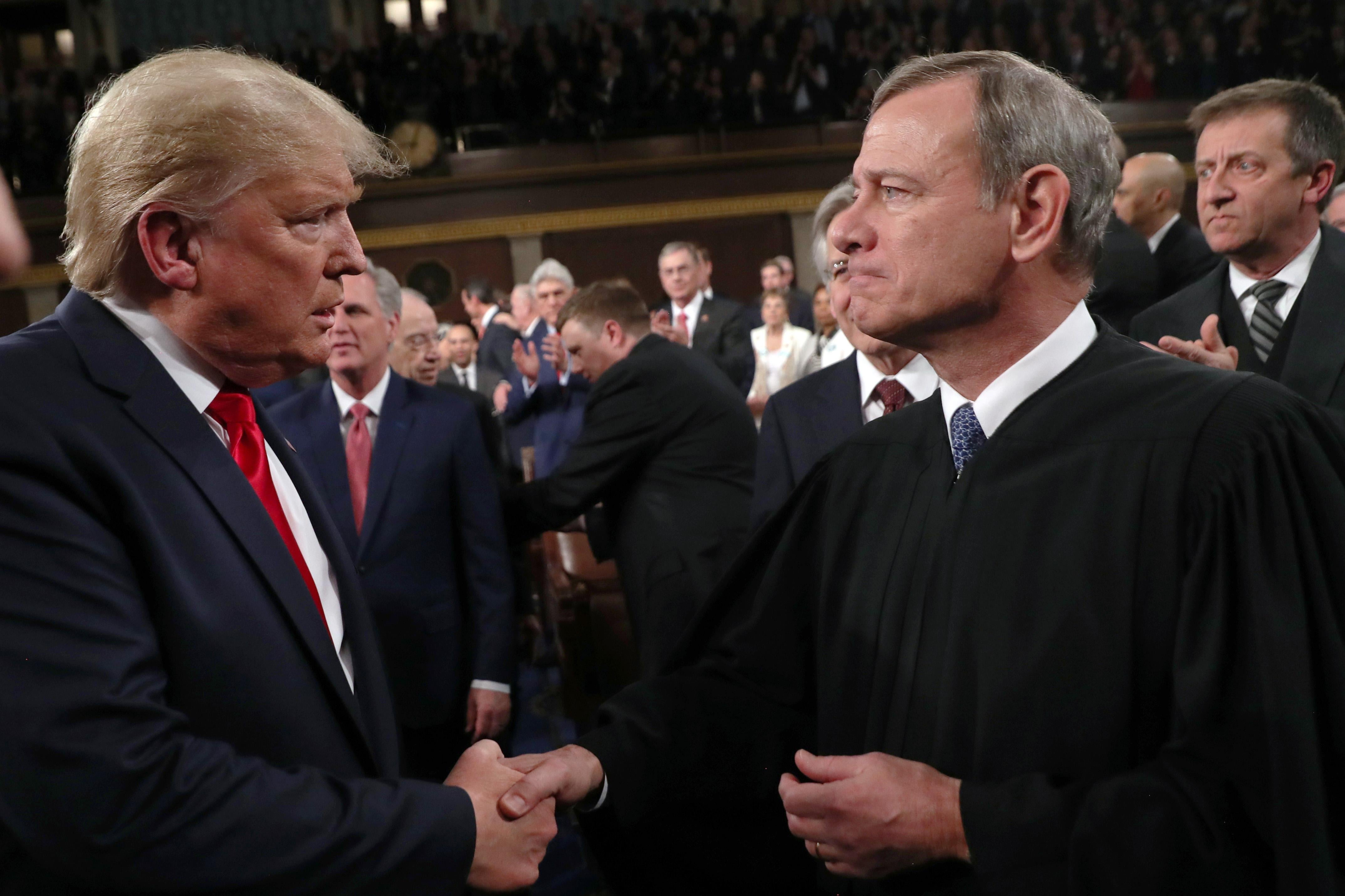 Donald Trump locks eyes with John Roberts as the two men shake hands.