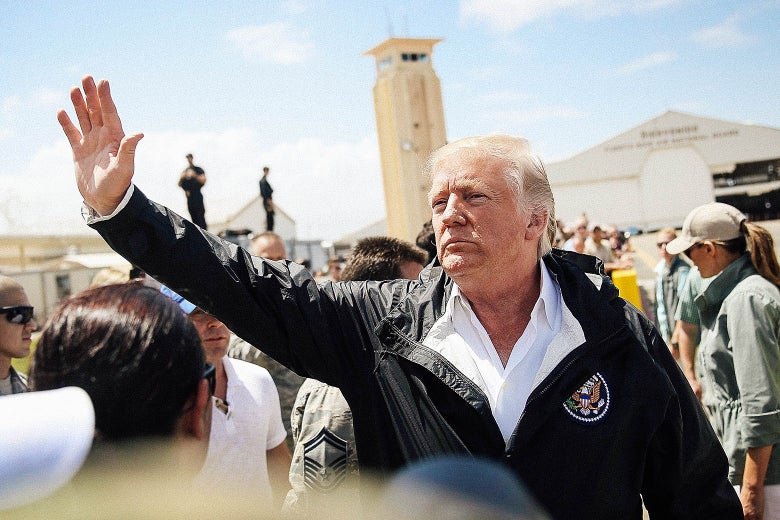 Trump, wearing a windbreaker, waves in a crowd at Muñiz air base.