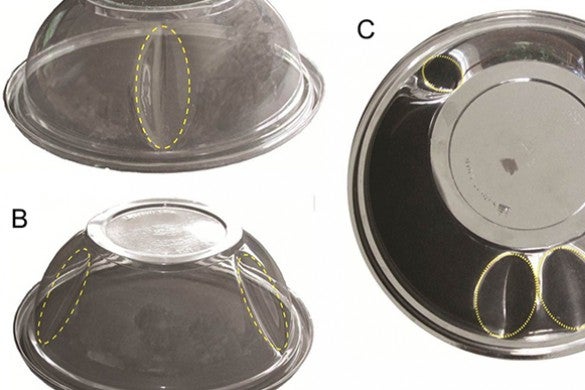 Three inverted plastic fruit bowls are marked with dimples in various locations on the bowls.
