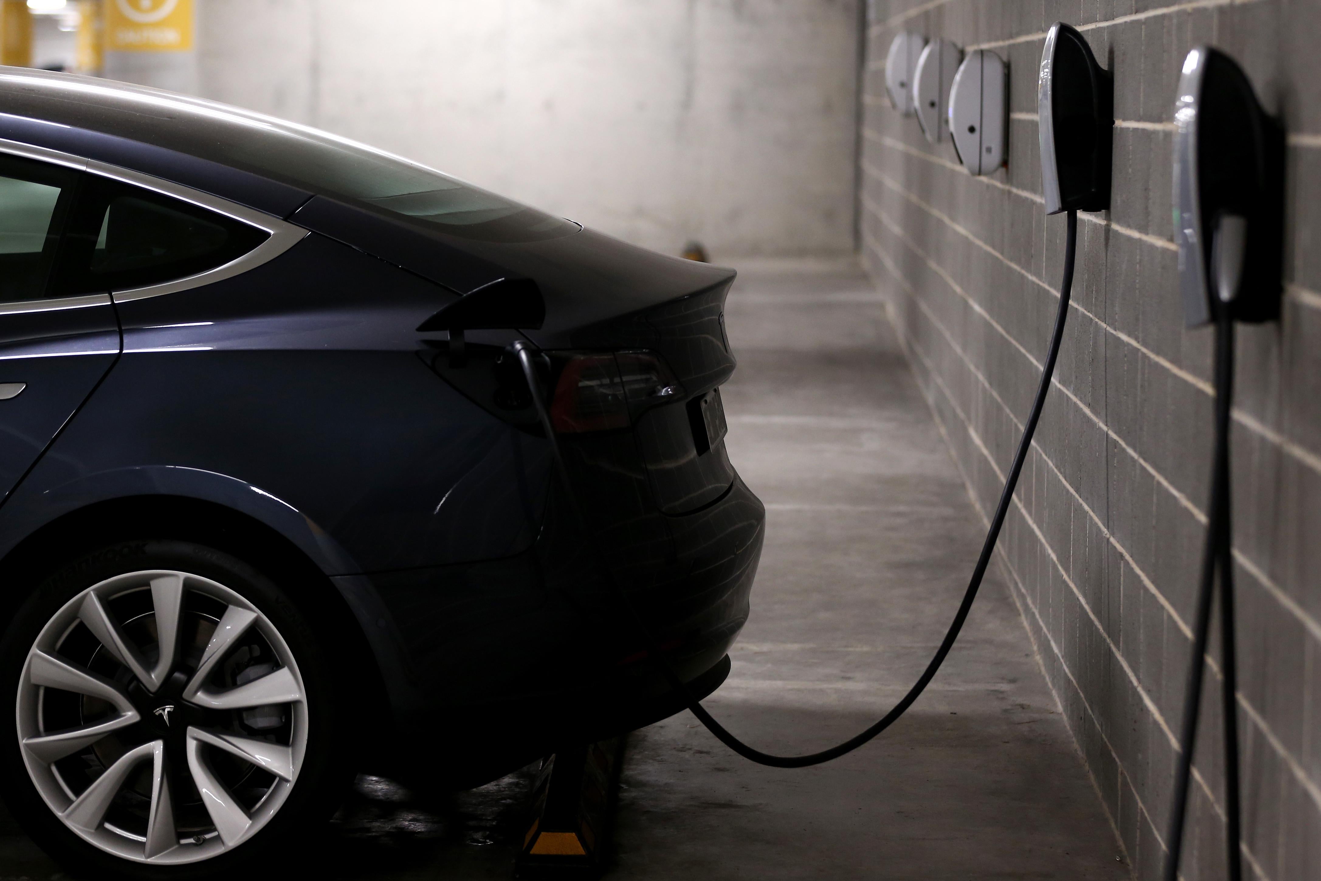 An electric car is seen plugged into an outlet on a brick wall.