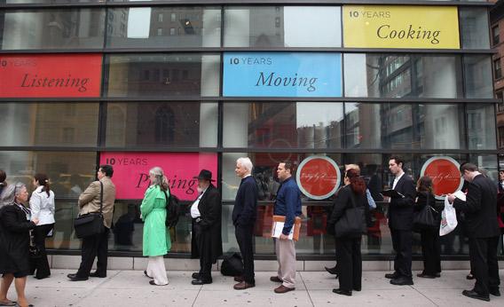 Unemployed people stand in a line that stretched around the block to enter a job fair.
