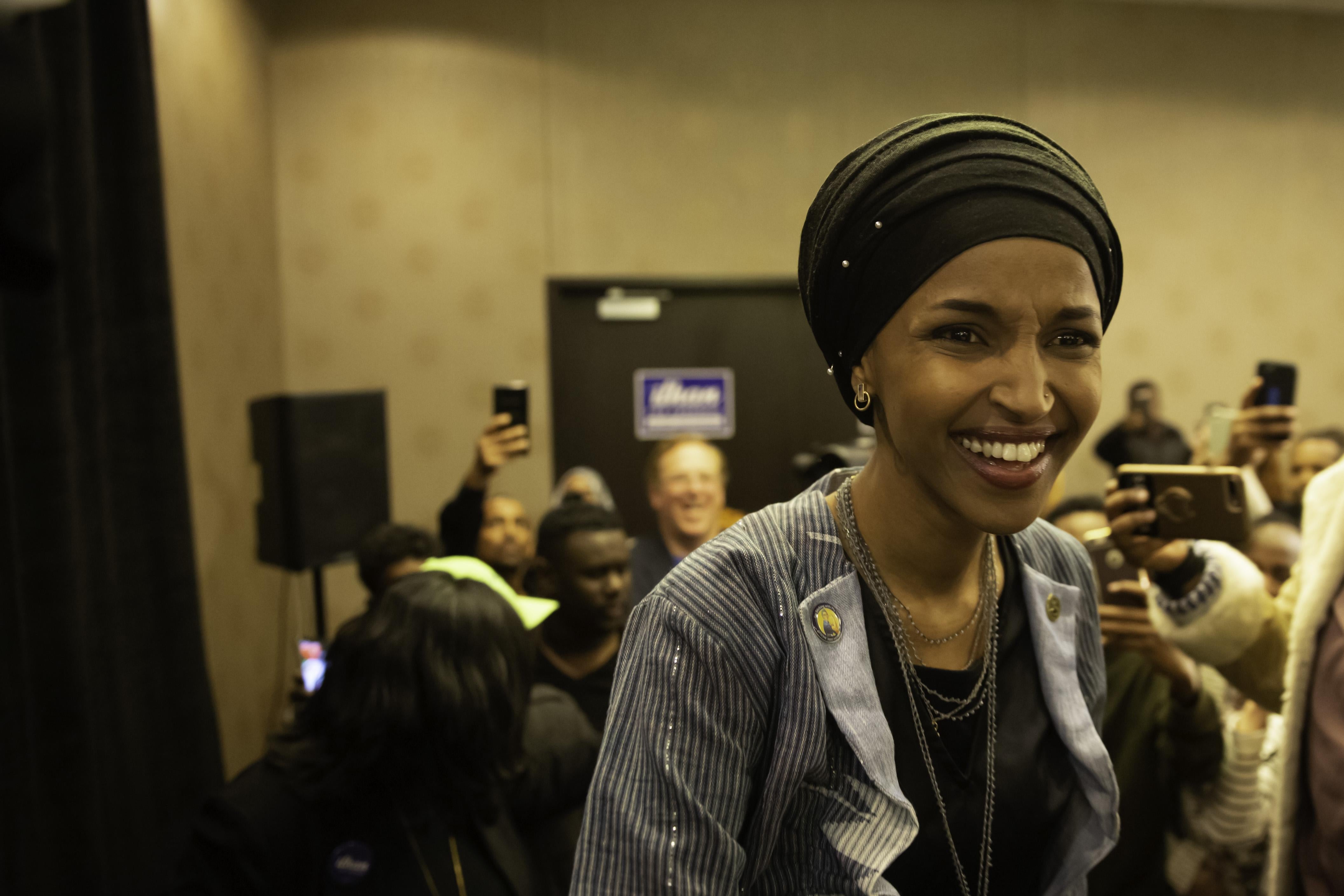 Ilhan Omar smiling, with a crowd behind her.