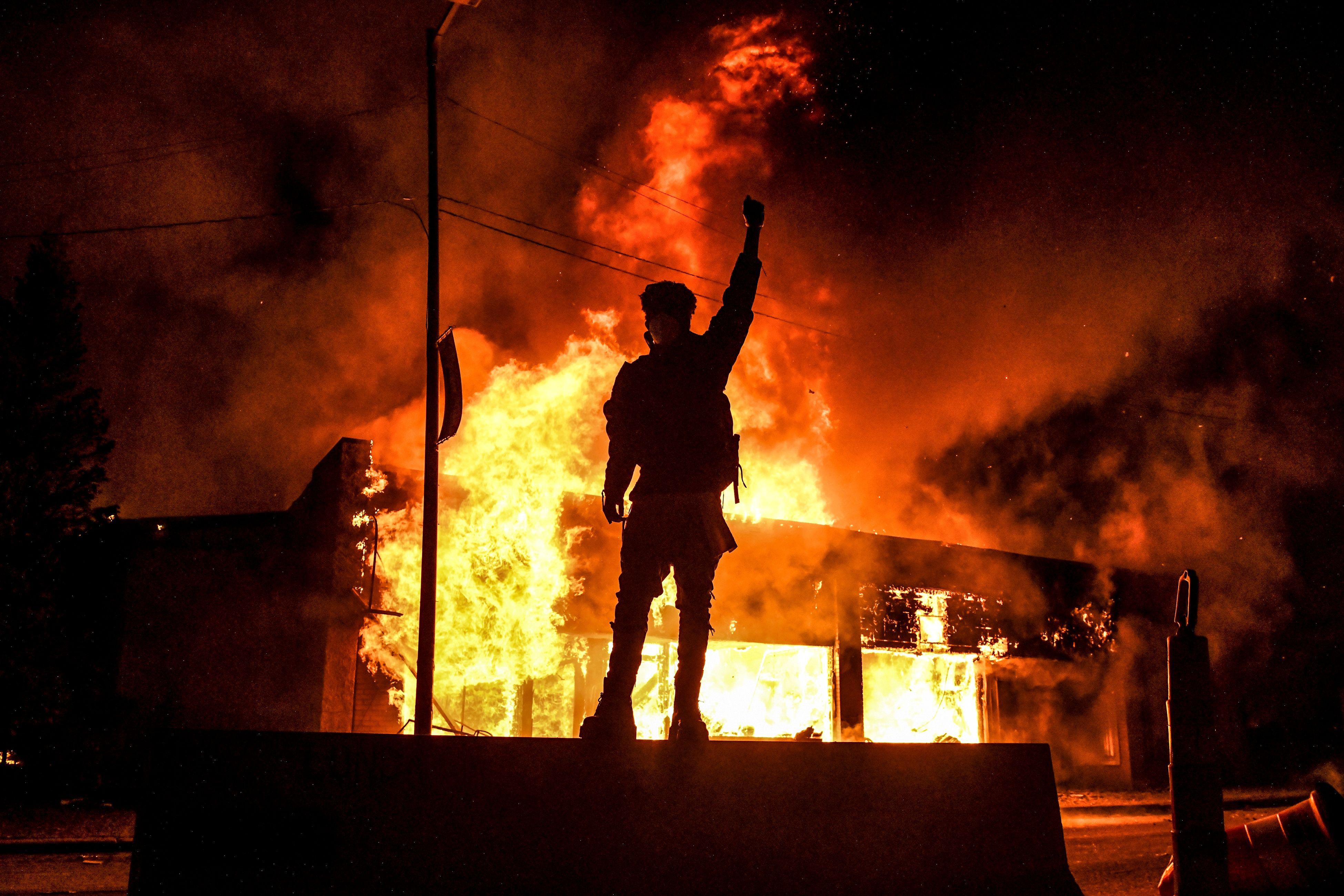 A protester stands in front of a burning in Minneapolis.