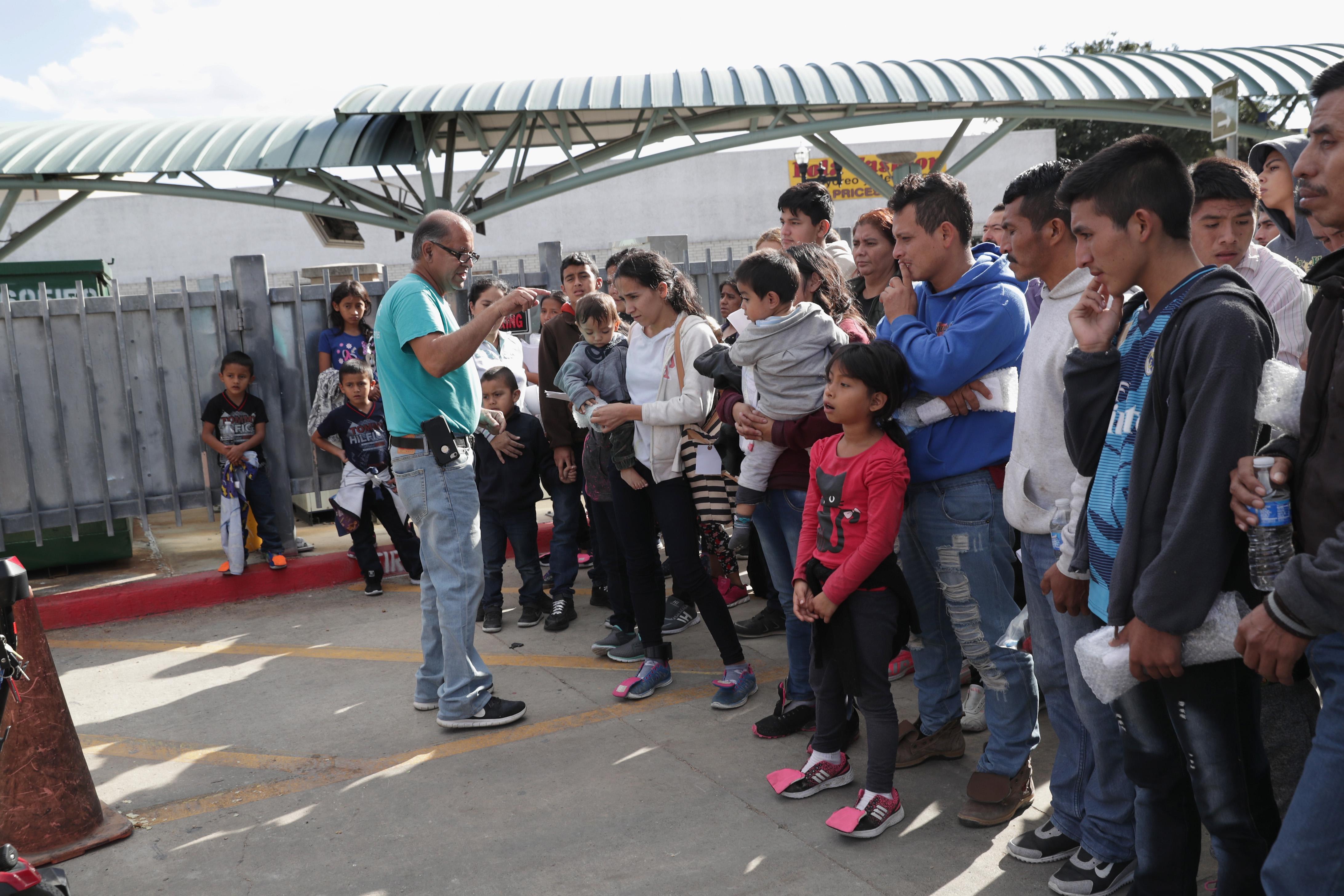 One man addresses a large crowd of immigrants outside