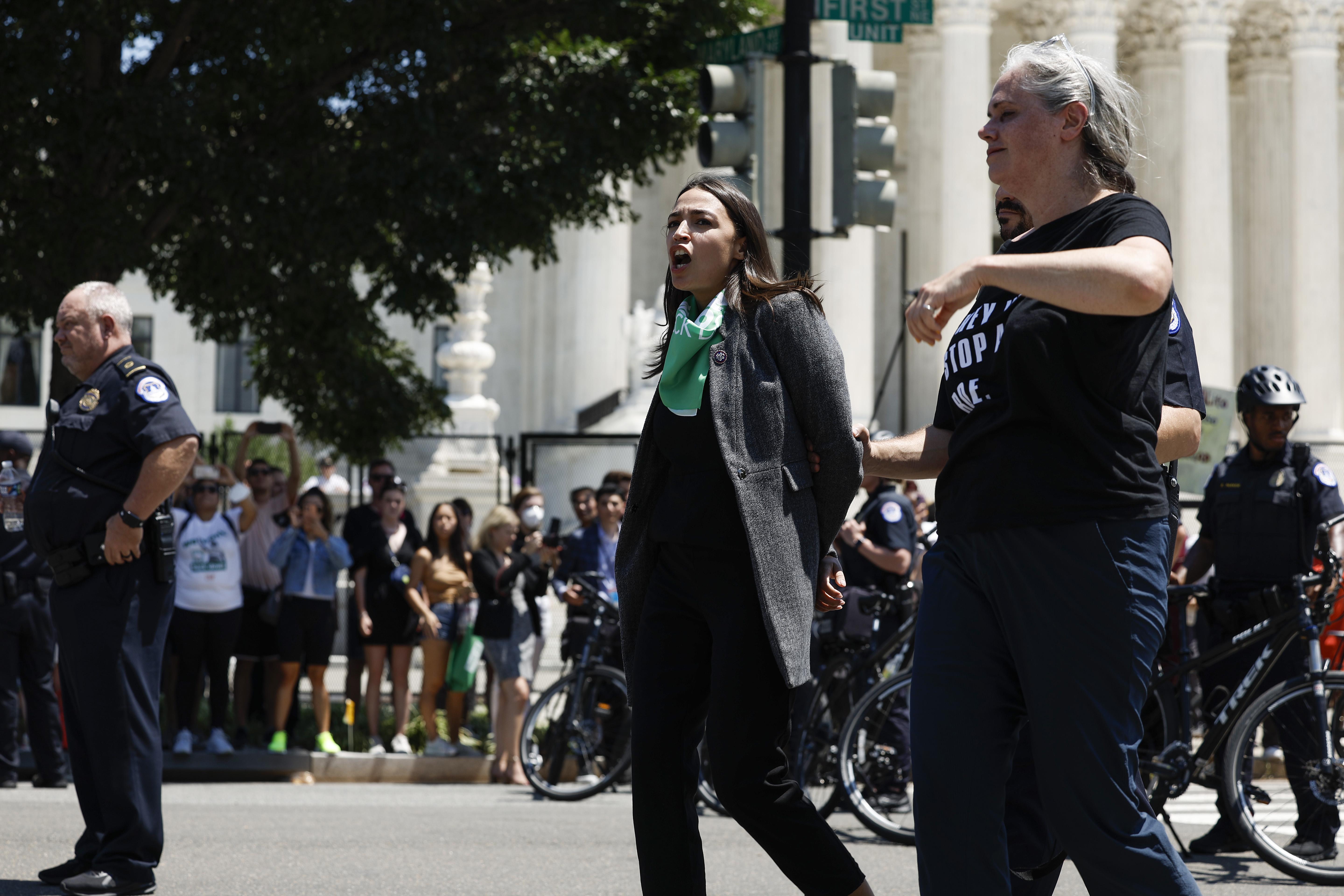Rep. Alexandria Ocasio-Cortez is led away by U.S. Capitol Police officers after participating in a protest outside the Supreme Court in support of abortion rights. 