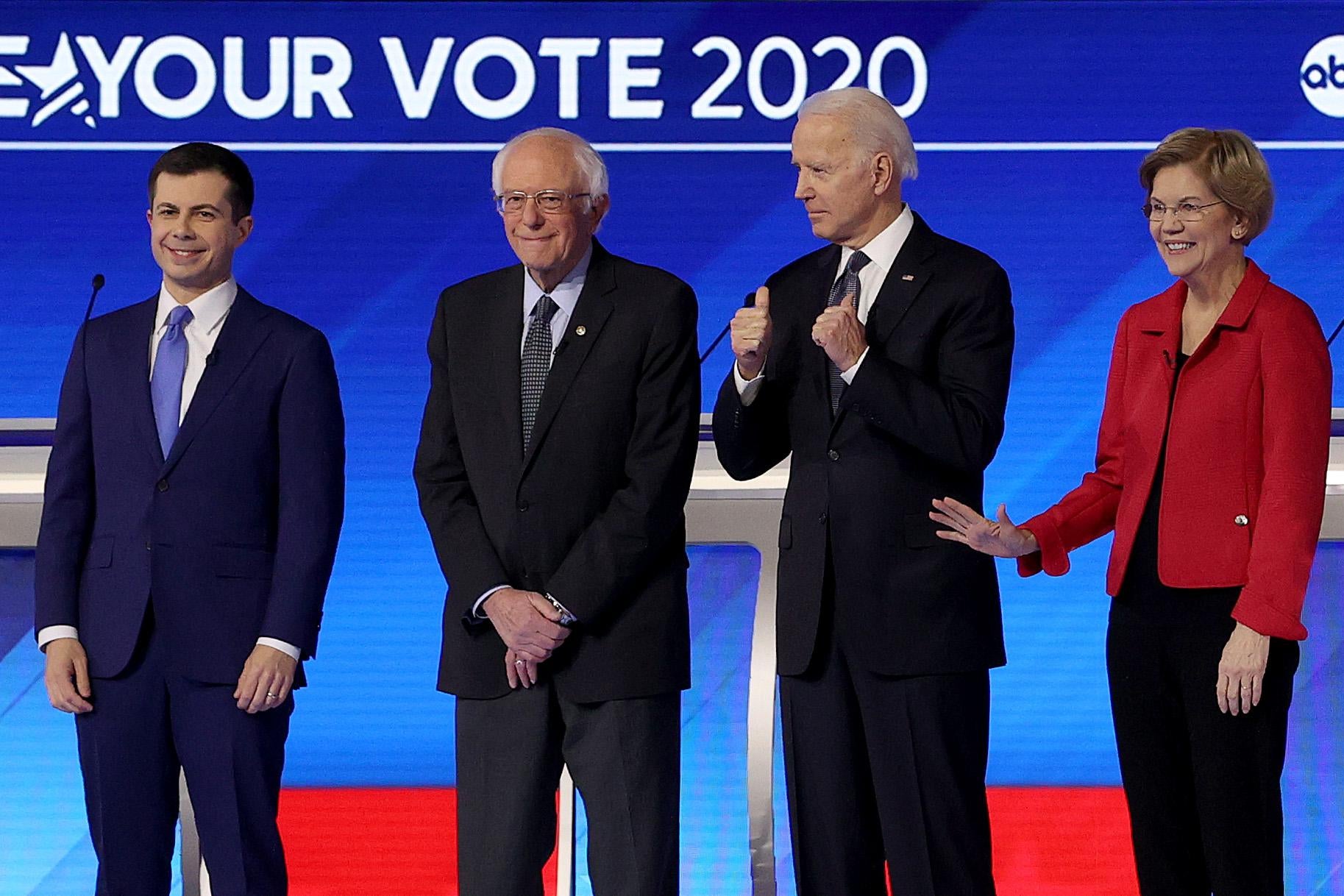 Pete Buttigieg, Bernie Sanders, Joe Biden, and Elizabeth Warren stand in a row on the debate stage.