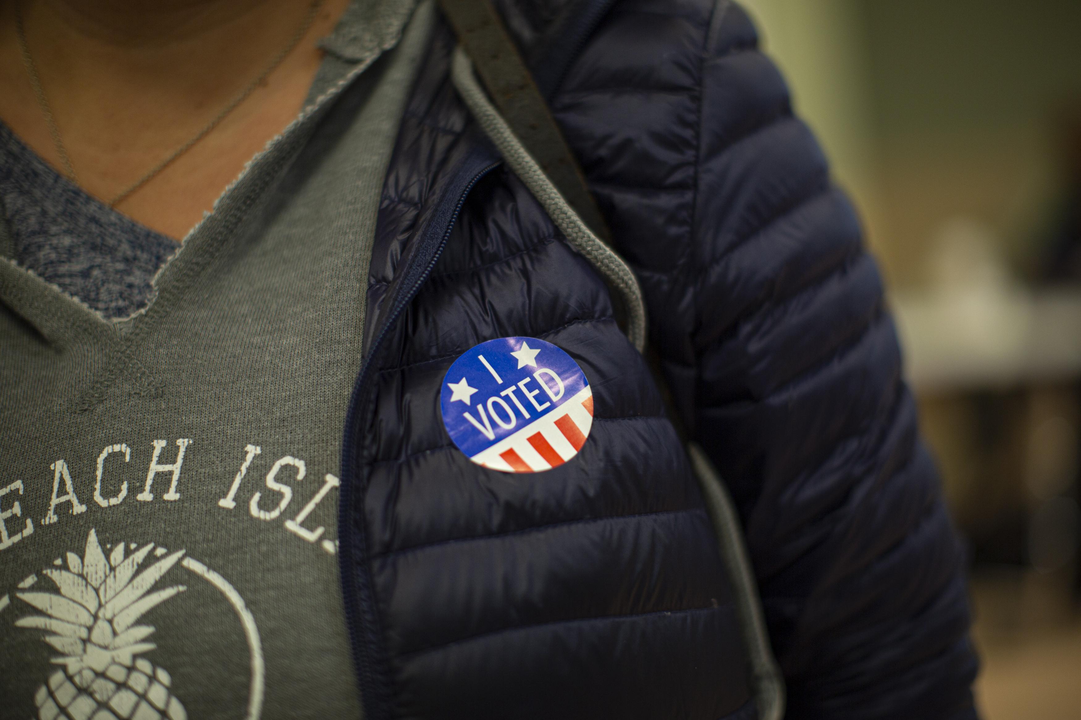 A woman wears a sticker after casting her vote at a polling station.